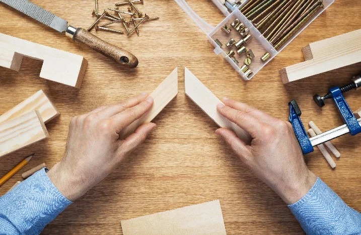 Hände fügen zwei Holzstücke zusammen.